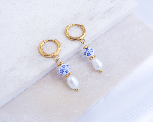 Pair of gold hoop earrings with blue and white bead accents on a light background. Portuguese Ceramic Pearl Mini Earrings on display, Mini Azulejo Earrings from Portugal, Portuguese Tlle Jewelry, Blue White Flower Porcelain Earrings
