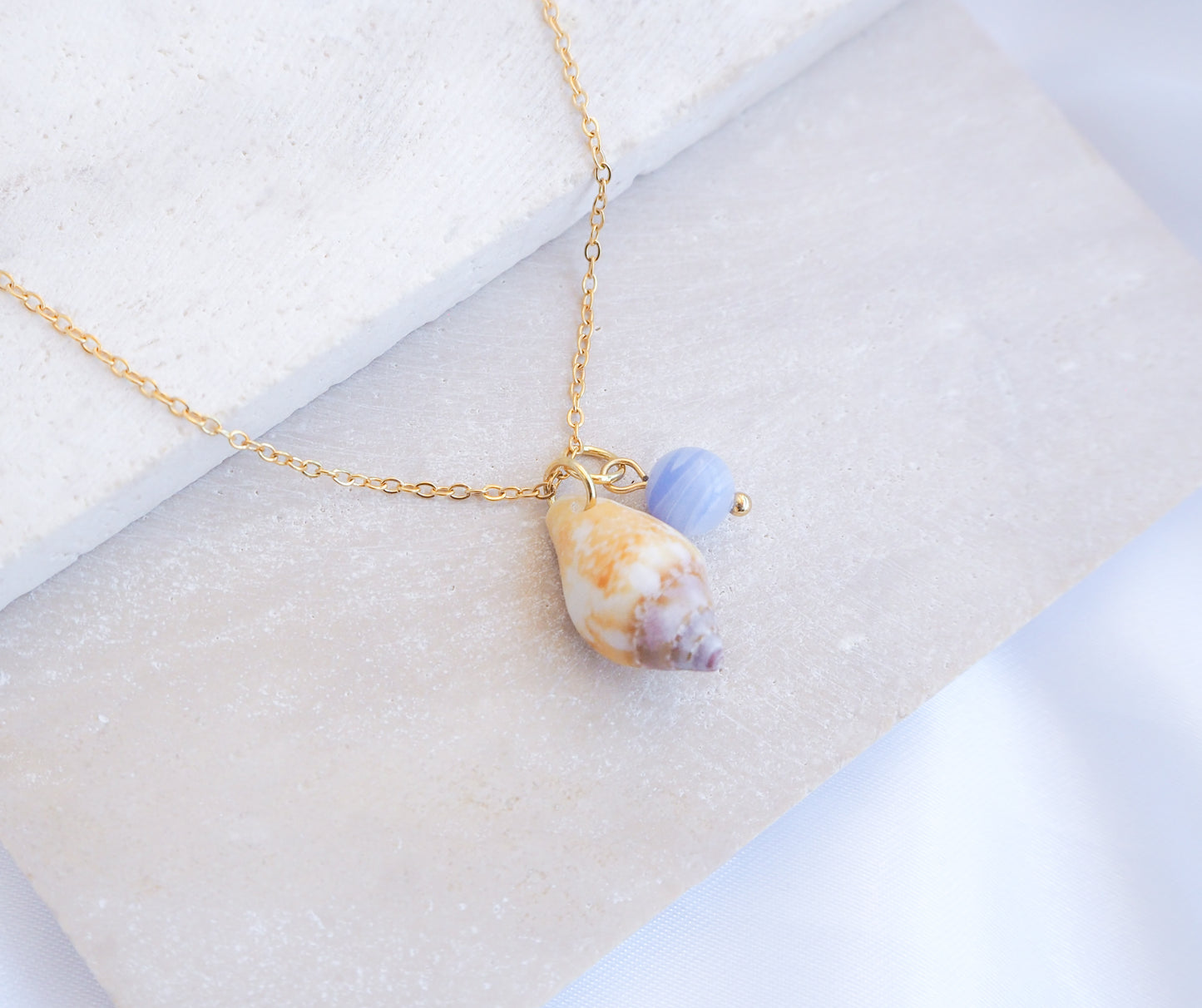 Tiny Light Rustic Dove with Angelite Gemstone Necklace displayed on stone