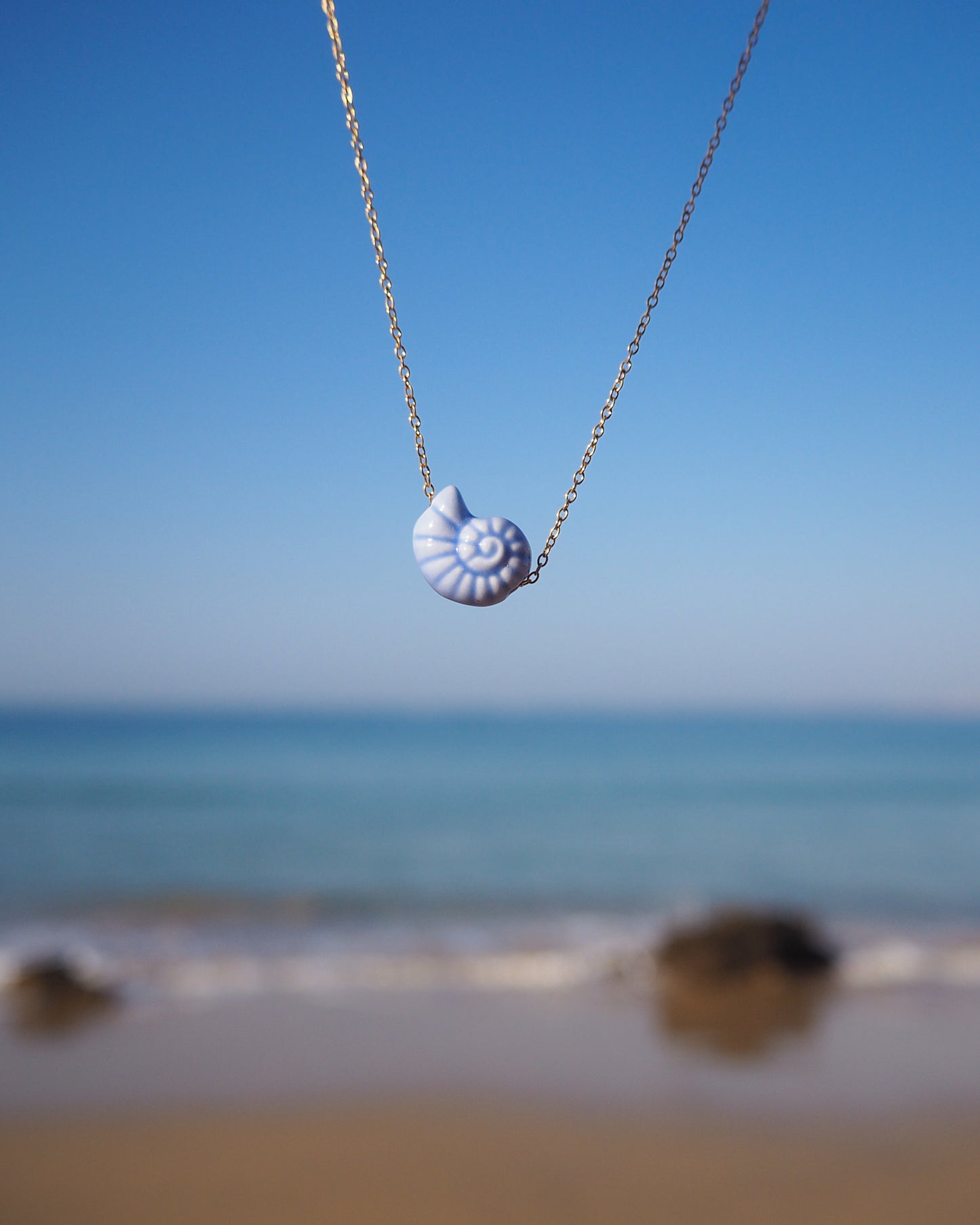 White Ceramic Seashell Nautilus Gold Necklace with ocean background of Portugal
