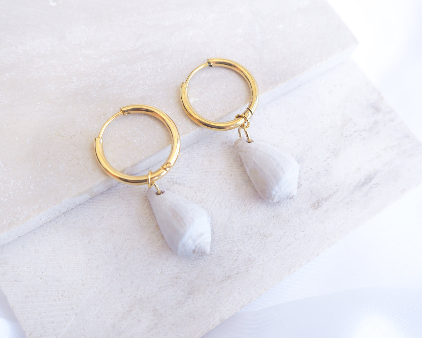 Light Mediterranean Cone Shell Gold Earring Hoops displayed on stone, handpicked cone shells from Portugal, 18k gold stainless steel shell earring hoops, seabylou 