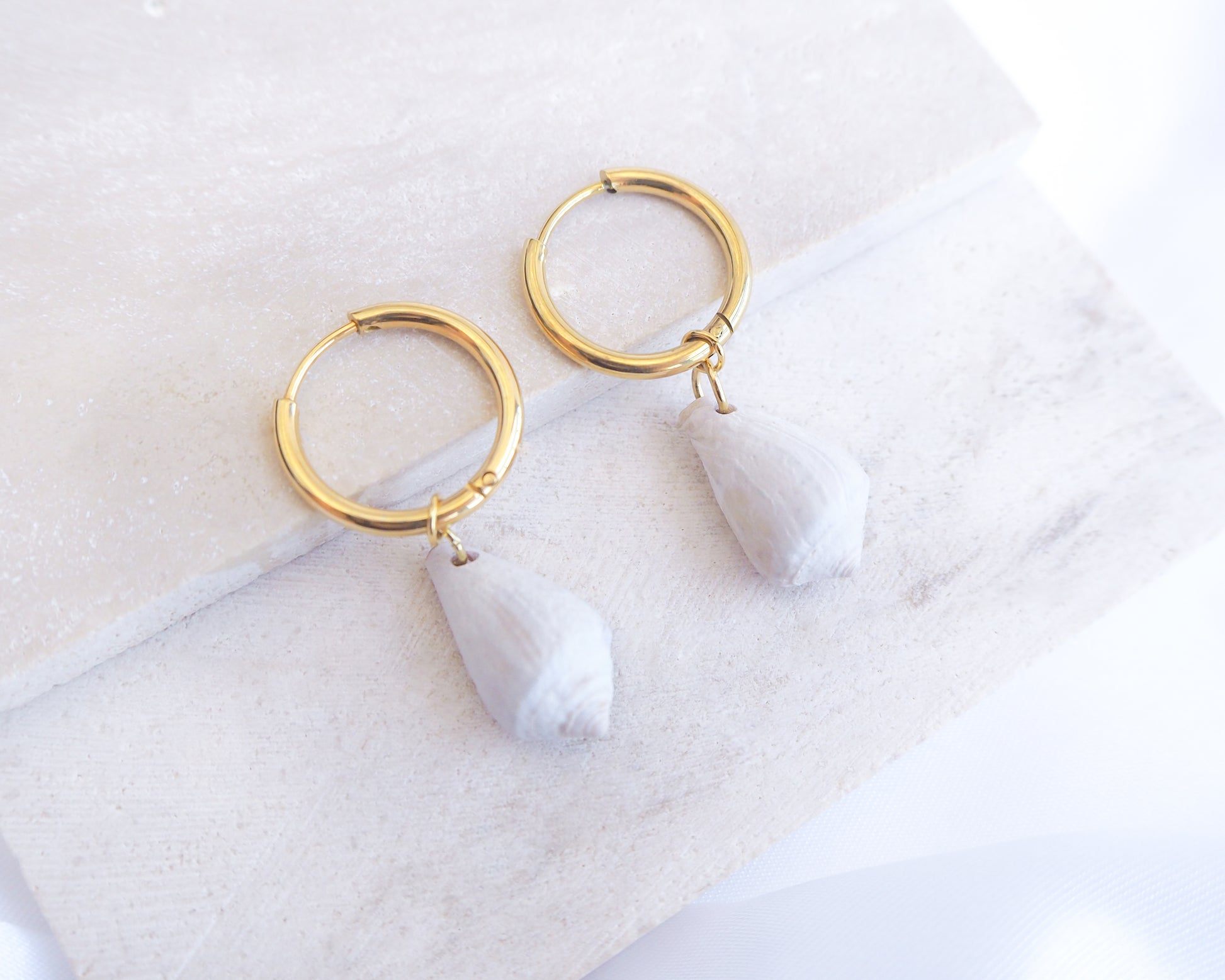Light Mediterranean Cone Shell Gold Earring Hoops displayed on stone, handpicked cone shells from Portugal, 18k gold stainless steel shell earring hoops, seabylou 