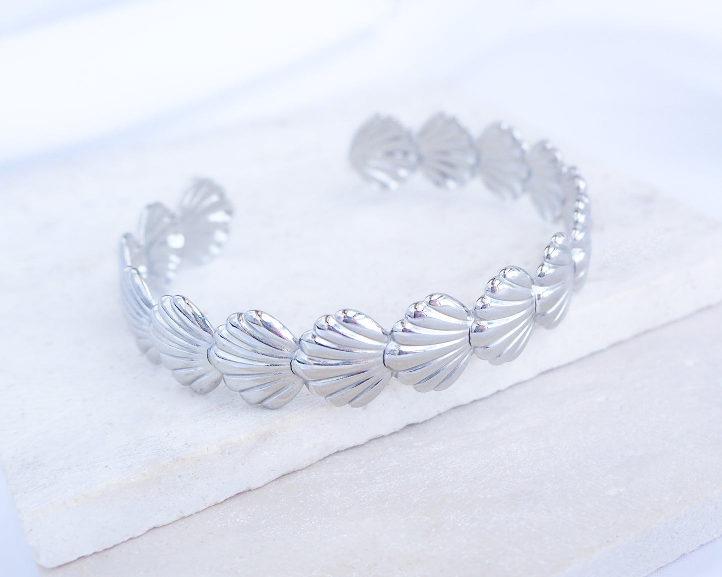 Silver bracelet with shell design on a white background
