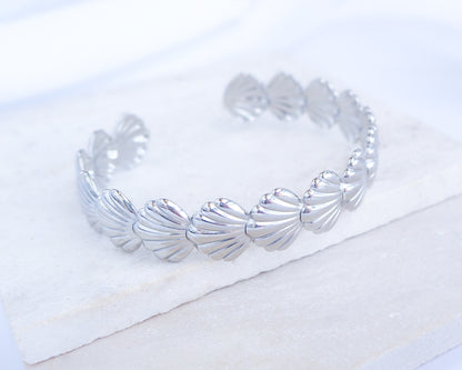 Silver bracelet with shell design on a white background