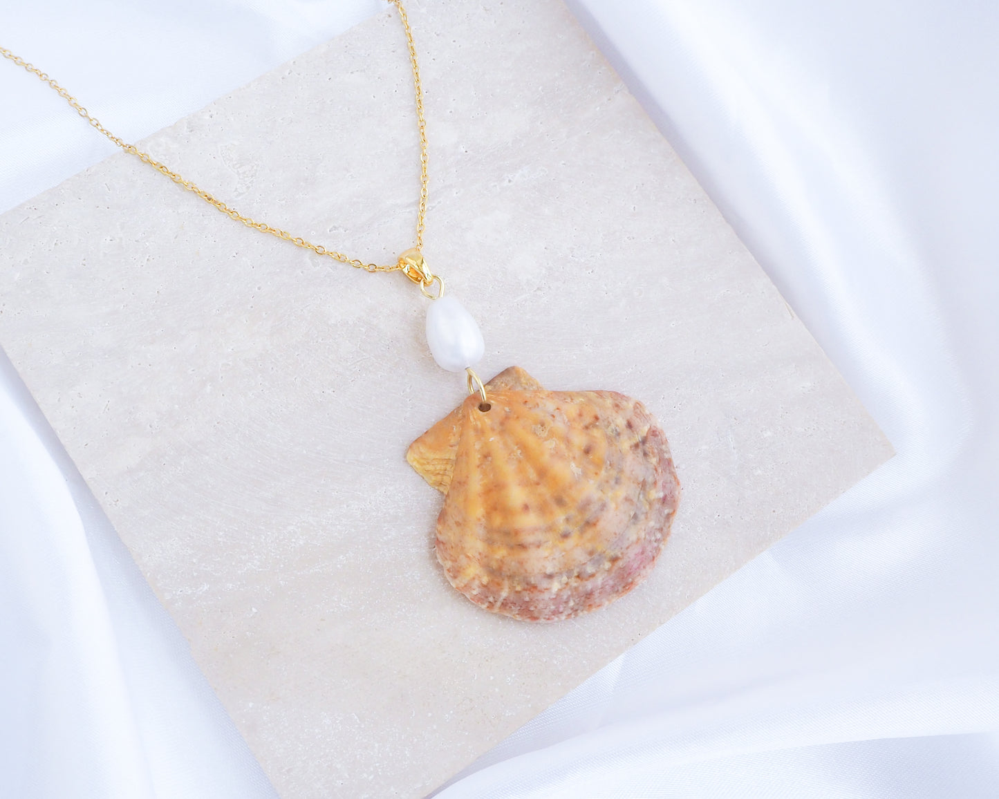 Shell pendant necklace with a pearl on a beige cushion. Orange Pink Scallop Shell Pearl Gold Necklace on stone displayed, Scallop Shell handpicked from Portugal 