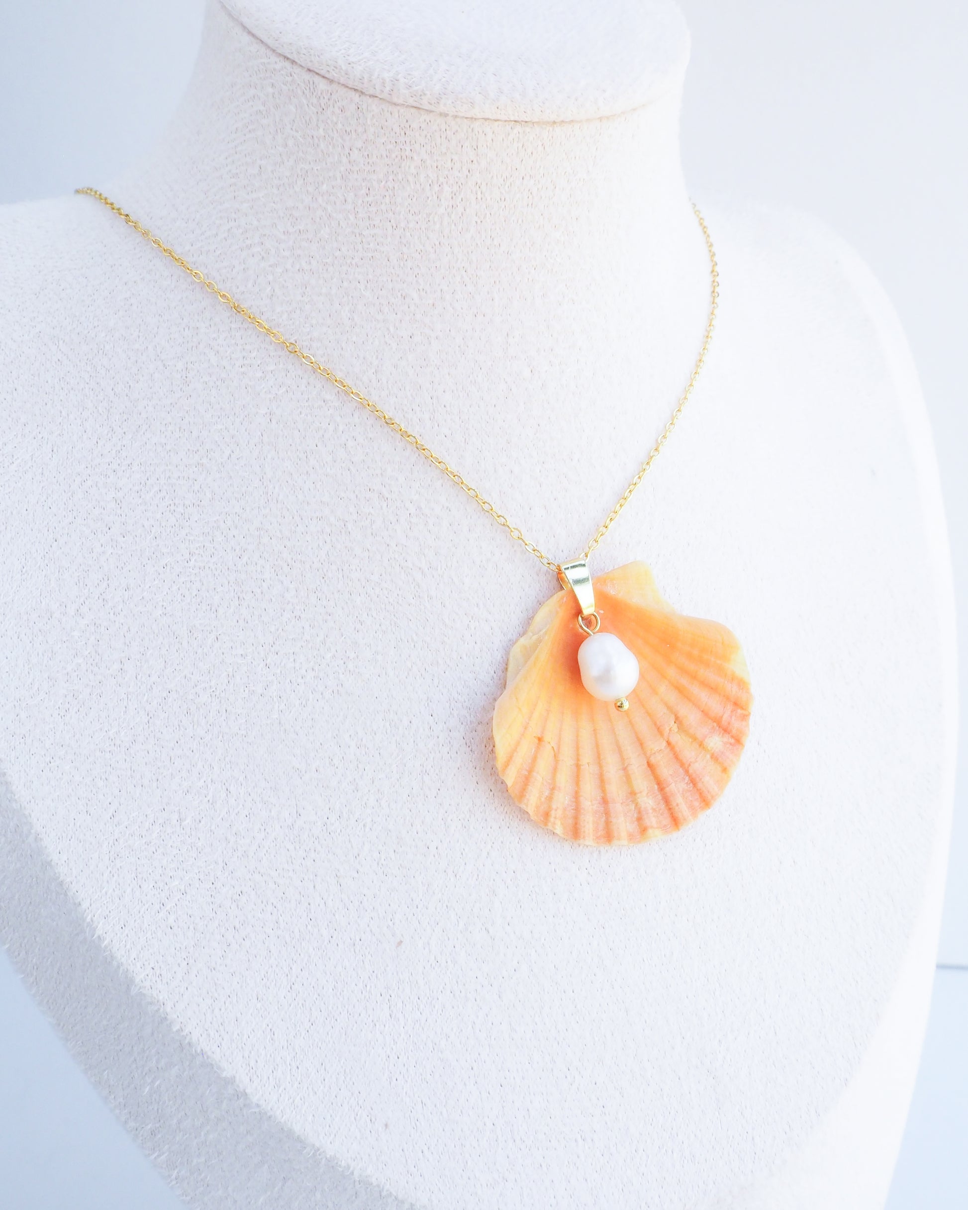 Display wearing Coral Orange Scallop Shell Pearl Gold Necklace II on stone displayed, Pilgrims Scallop Shell from Portugal with freshwater pearl and gold chain. 