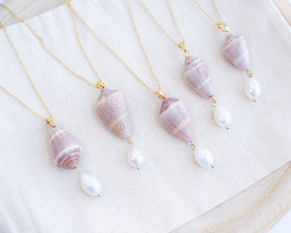 Necklaces with shell and pearl pendants on a white surface. Mix of Mediterranean Cone Shell Pearl Necklaces from Portugal on display, handpicked cone shell from Algarve, Freshwater pearl and 18k gold stainless steel chain