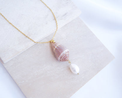 Necklace with shell and pearl pendant on a white surface. Mediterranean Cone Shell Pearl Necklace Reversed from Portugal on stone displayed, handpicked cone shell from Algarve, Freshwater pearl and 18k gold stainless steel chain