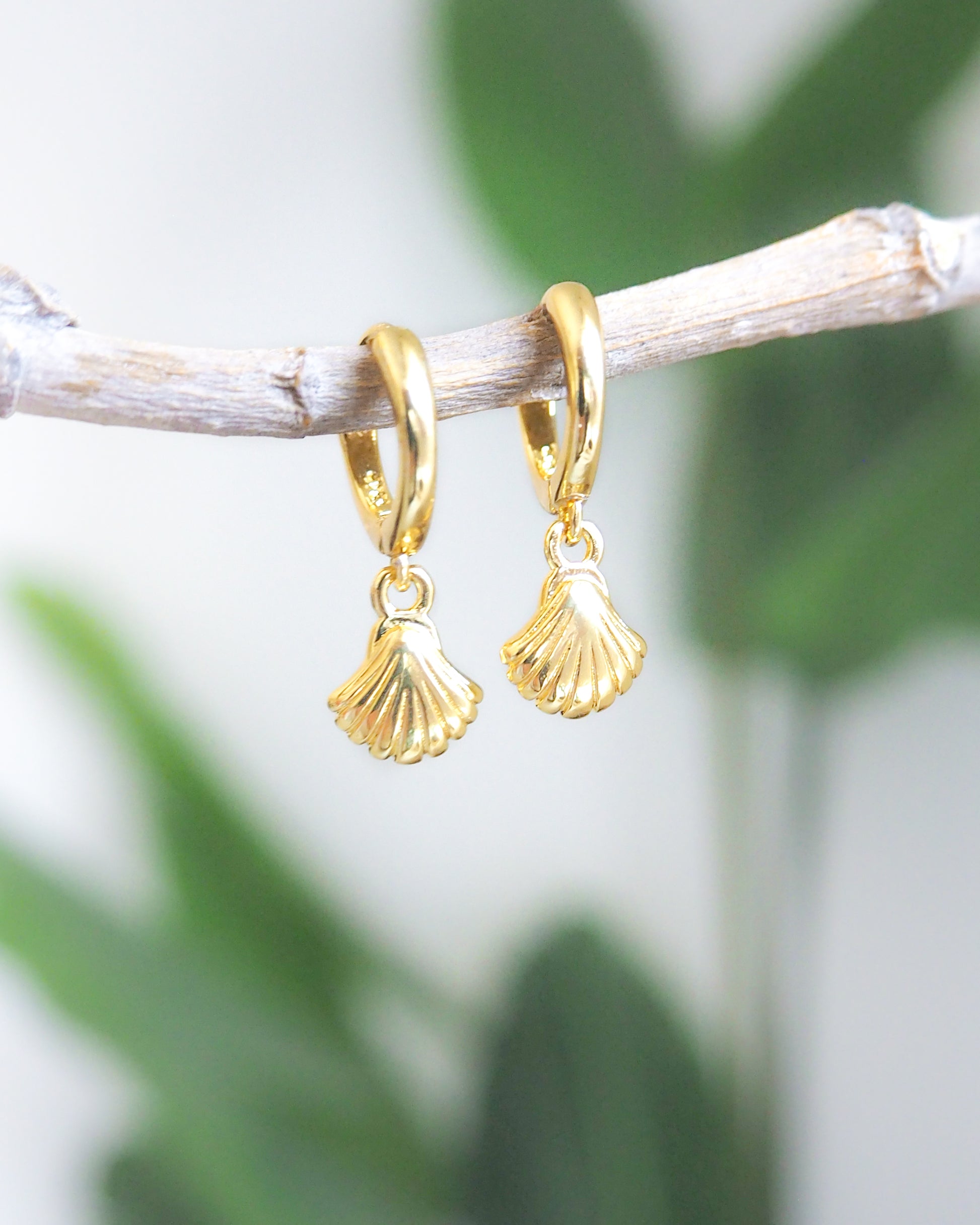 Front view of Gold Tiny Seashell Huggie Earrings with white background and green plant details, 14k gold vermeil or 925 Sterling Silver, Dainty Tiny Scallop Shell Pendant Hoop Earrings, Sea by Lou jewelry, Minimalistic Coastal Style