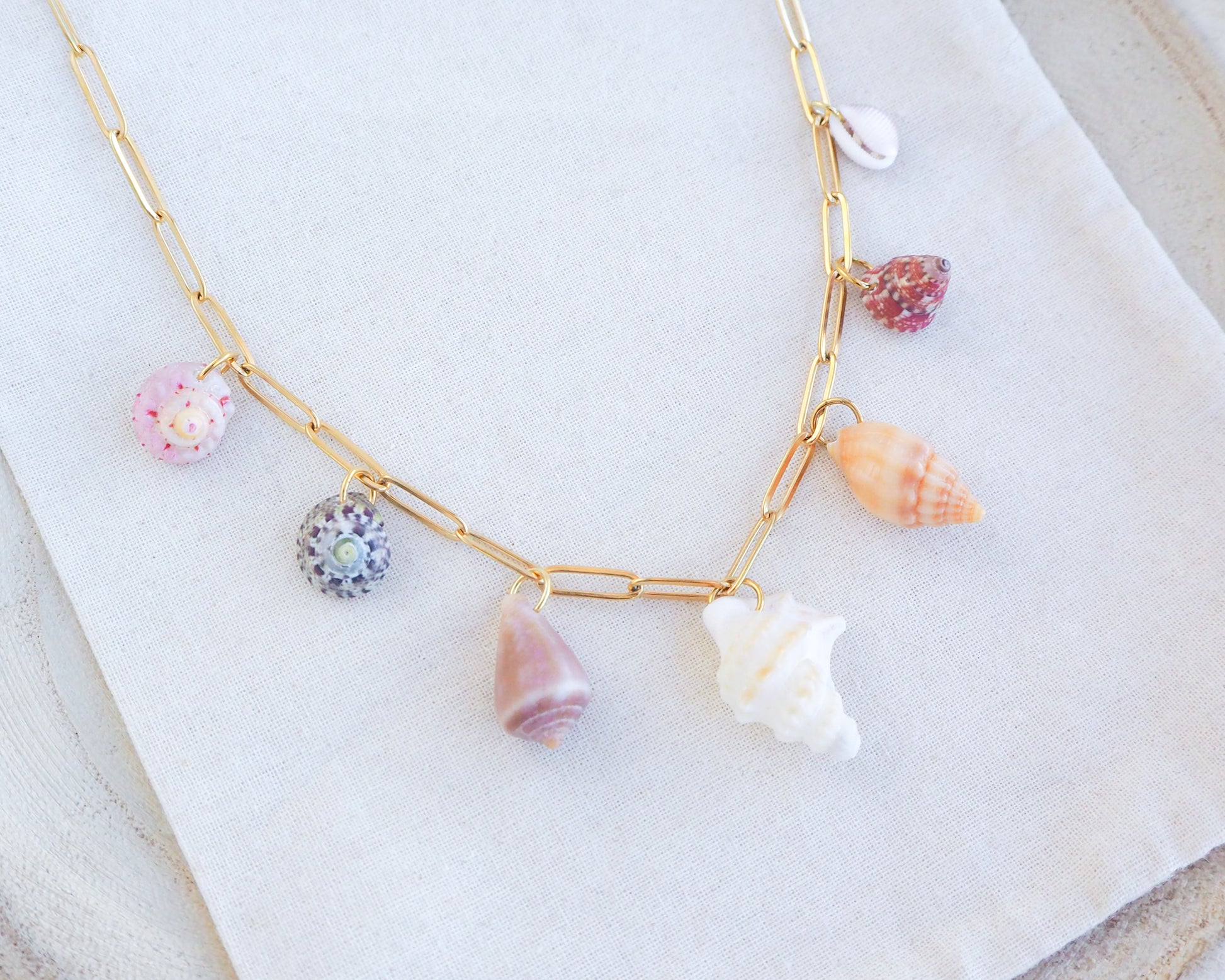 7 Shell Charm Necklace on display, ocean-inspired jewelry from Portugal, Pelican Foot Shell, Rustic Dove, Cone Shell, Cowrie Shell