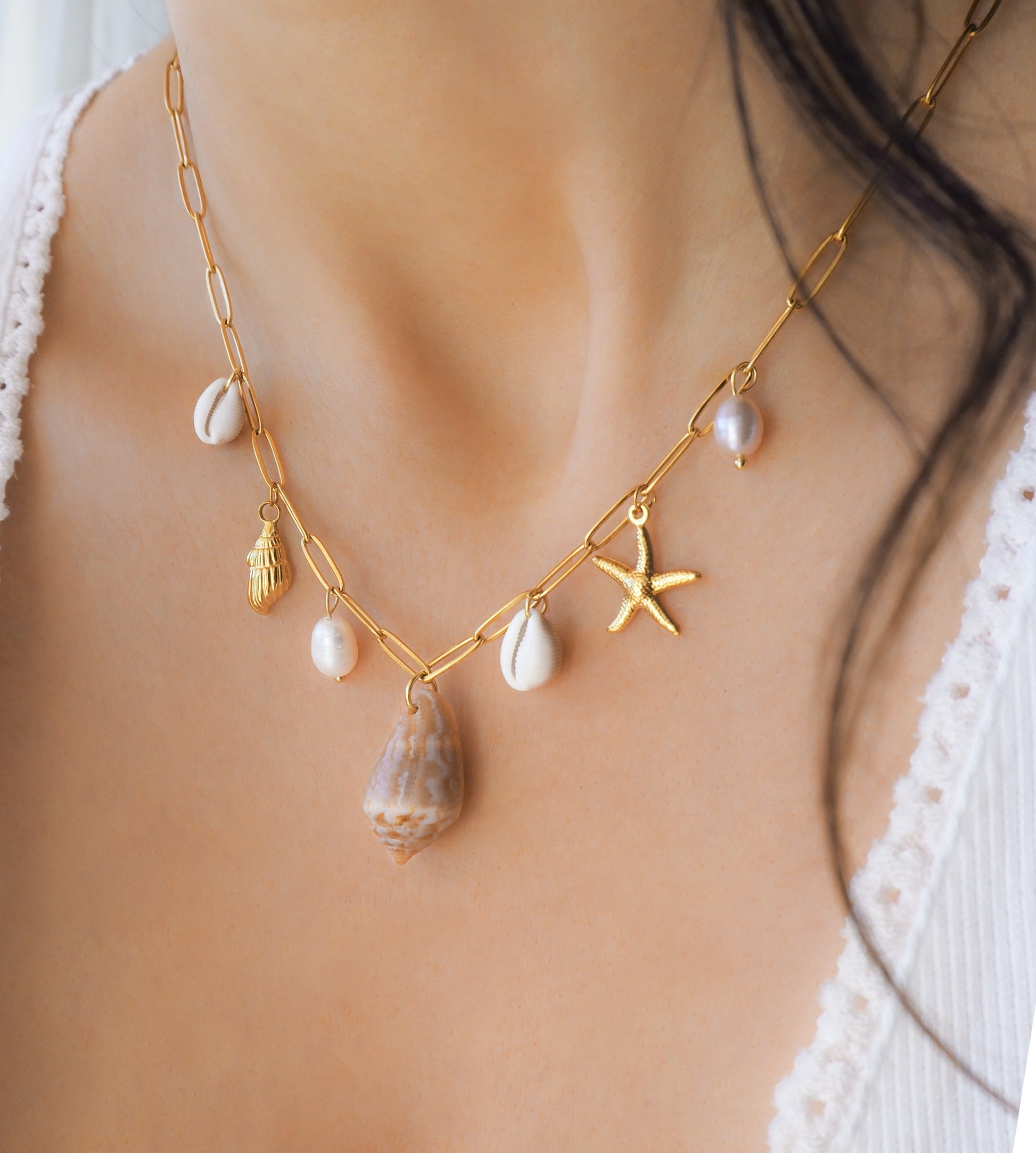 Gold Ocean Shell Charm Necklace on model side view, with cone and cowrie shells, freshwater pearls, starfish sea star shell pendants. 
