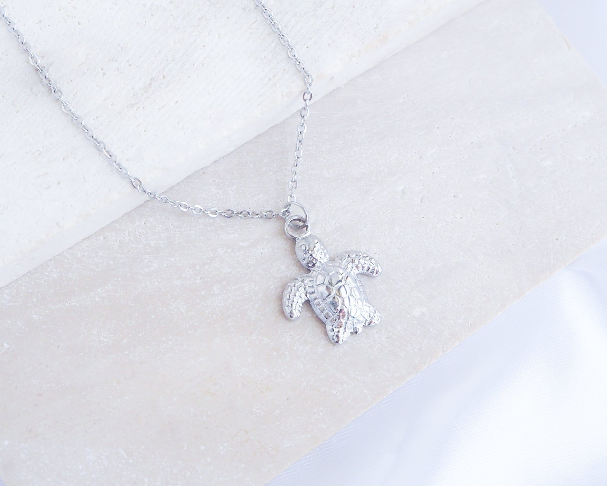 Silver Baby Turtle Necklace displayed on stone, Cute Sea Turtle Necklace