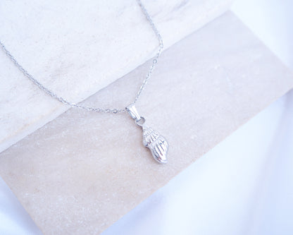 Silver Conch shell pendant necklace on a white marble surface
