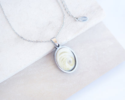 Eye of Saint Lucia Silver Necklace front view with plant background, silver stainless steel shiva eye pendant necklace, Saint Lucy Eye, operculum pendant