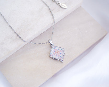 Close up of Portuguese Tile Necklace silver on stone displayed. Made with silver stainless steel and soft pink floral pendant inspired by the Portuguese Azulejo design pattern. 