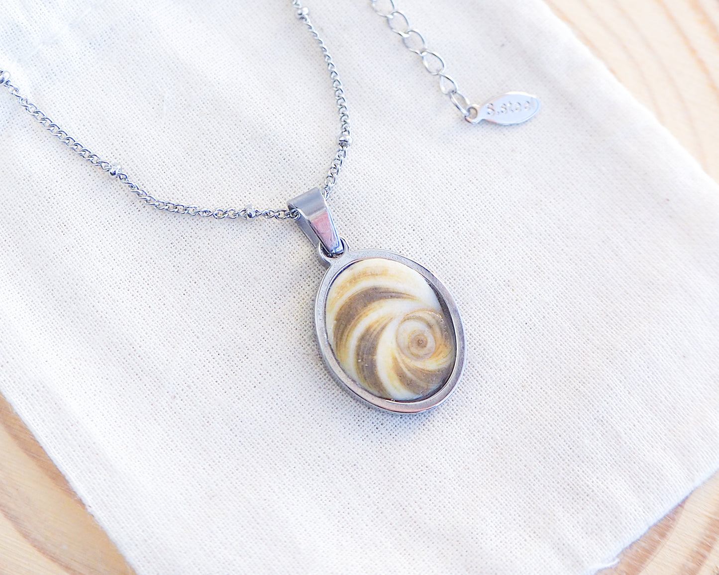 Khaki Green Eye of Saint Lucia Silver Necklace on cotton displayed, silver stainless steel shiva eye pendant necklace, Saint Lucy Eye, operculum pendant