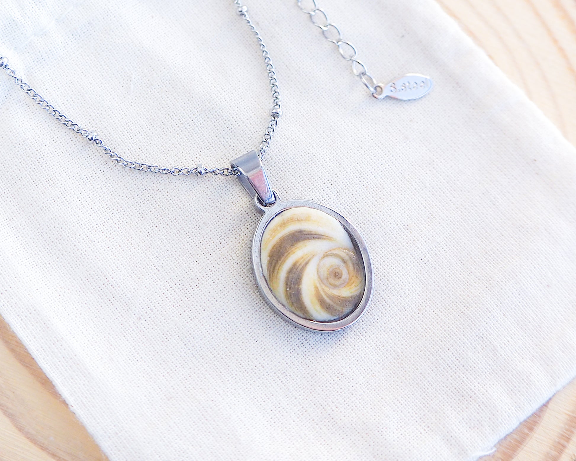 Khaki Green Eye of Saint Lucia Silver Necklace on cotton displayed, silver stainless steel shiva eye pendant necklace, Saint Lucy Eye, operculum pendant