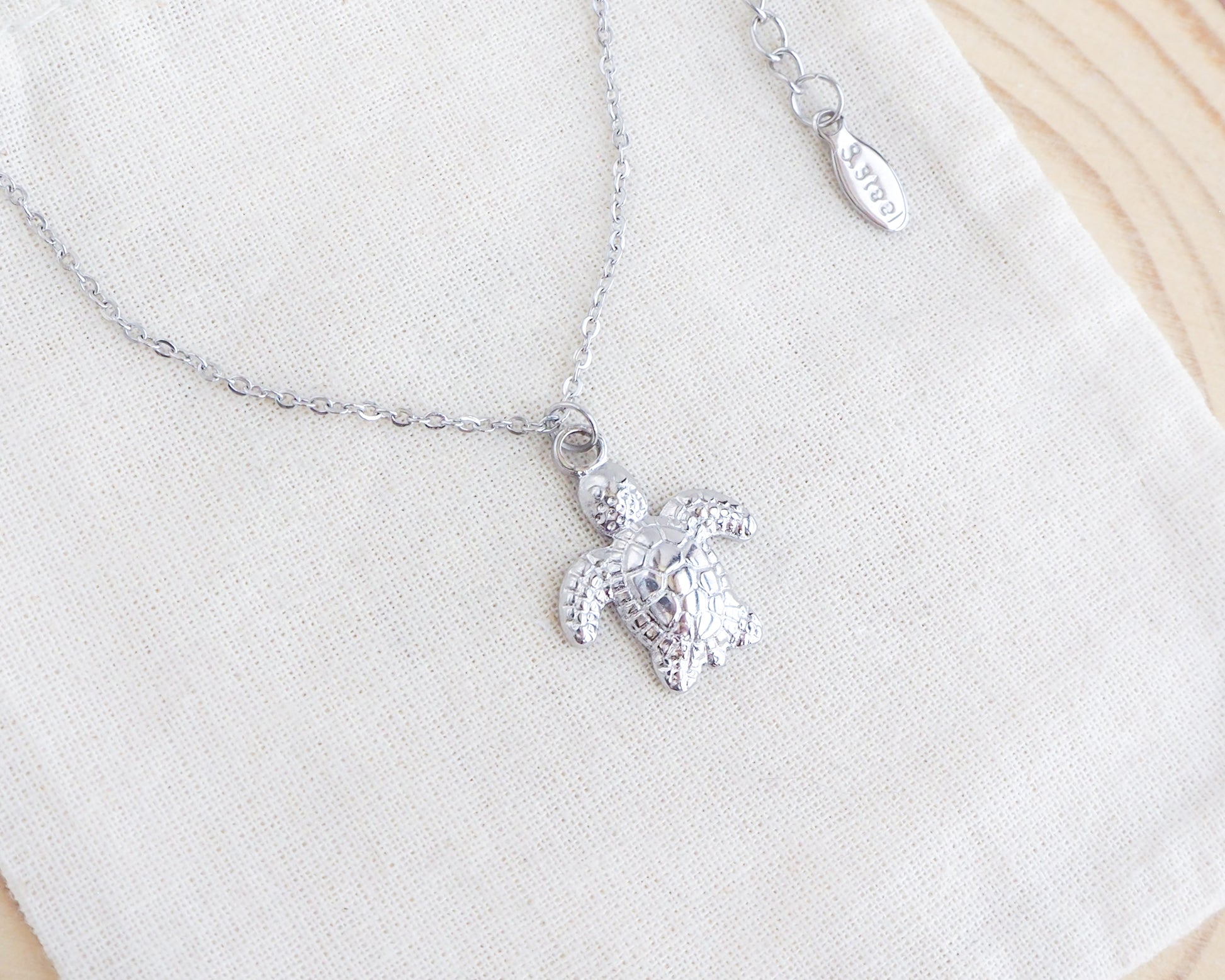 Silver turtle pendant necklace on a white background