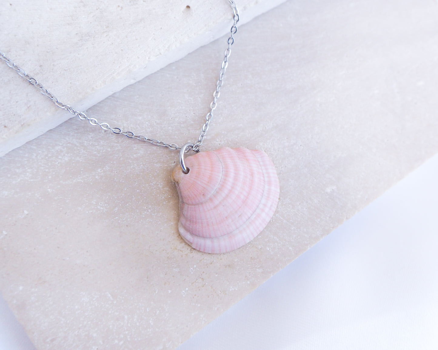 Soft Pink White Striped Venus Shell Silver Necklace from Portugal displayed on stone, Handpicked seashell from Algarve Portugal with silver necklace chain, perfect gift for beach girls, holiday memory portugal