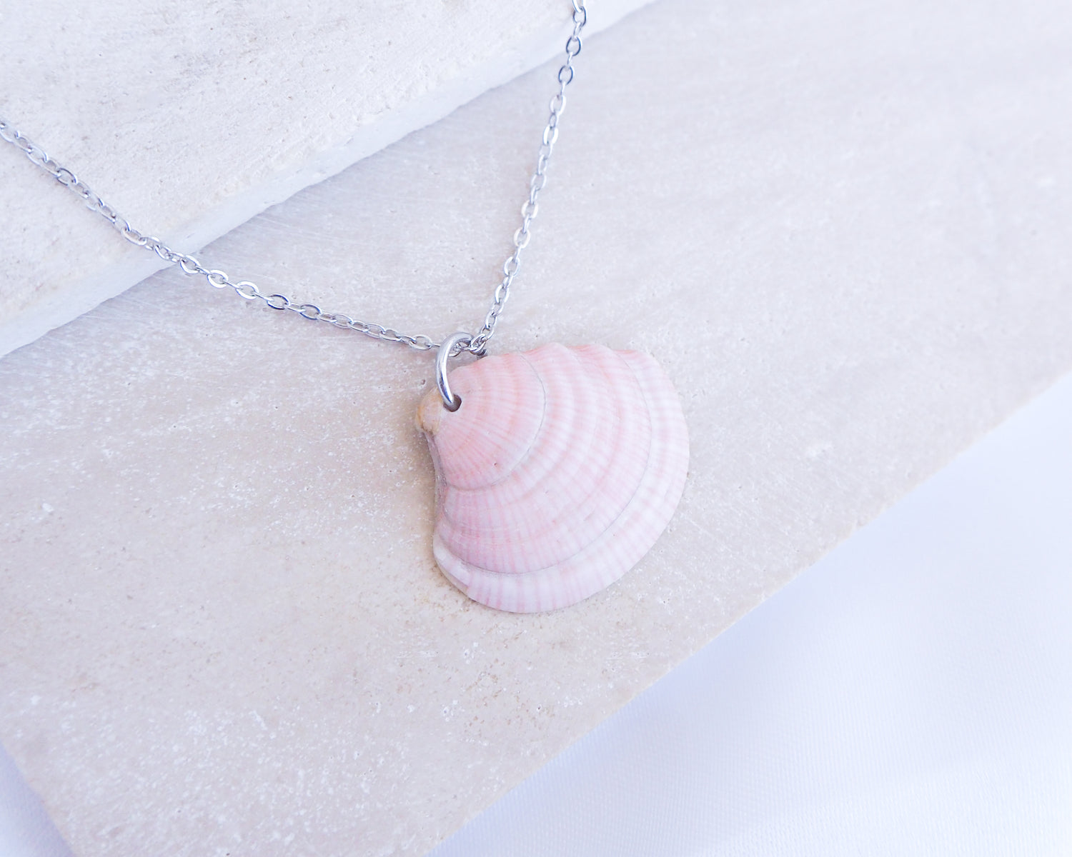 Soft Pink White Striped Venus Shell Silver Necklace from Portugal displayed on stone, Handpicked seashell from Algarve Portugal with silver necklace chain, perfect gift for beach girls, holiday memory portugal