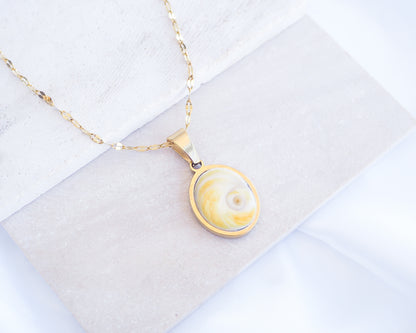 Soft Yellow Shiva Eye Necklace on stone displayed. Light Eye of Saint handpicked from Portugal, 18k gold stainless steel shiva eye pendant necklace, Saint Lucy Eye, operculum pendant