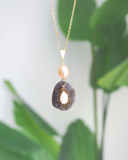 Front view of Striped Limpet Shell Rose Pearl Necklace with plant background, Dark Limpet Shell from Portugal with freshwater pearl and gold chain. 