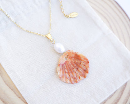 Close up of Tiny Coral Scallop Shell Pearl Necklace on cotton displayed
