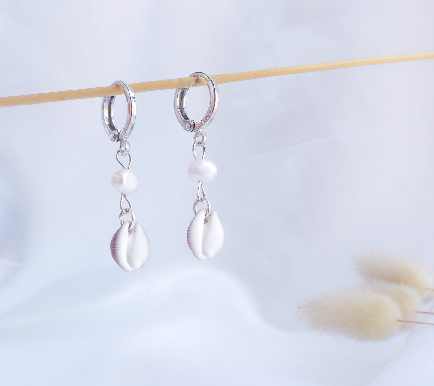 Front view of 925 sterling silver european cowrie shell earrings with freshwater pearls on white background. handpicked trivia monacha shell from portugal, coastal wedding jewelry