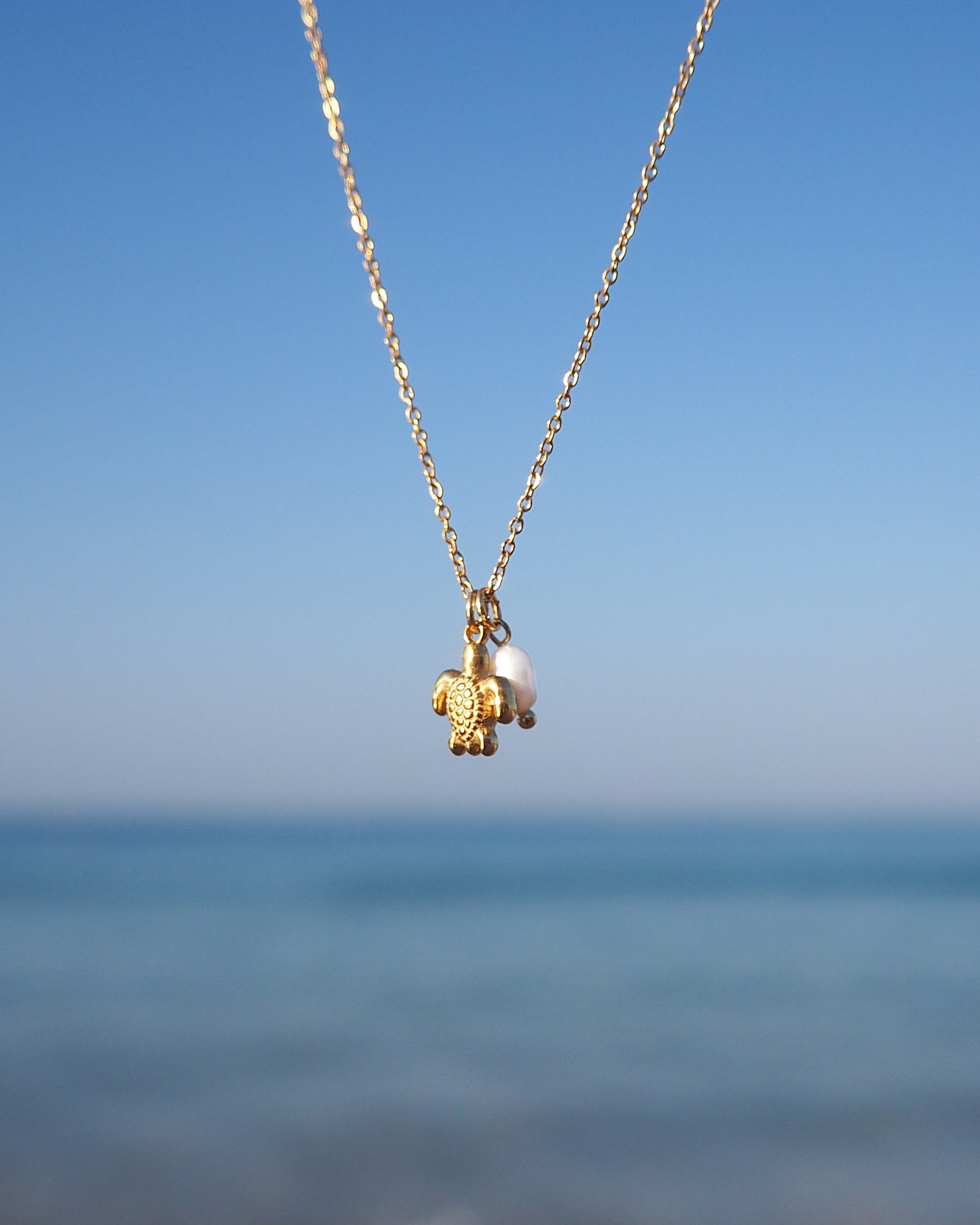 Close up of Tiny Turtle Pearl Necklace with ocean background, Gold Necklace with freshwater pearls and 18k gold turtle pendant, Minimalistic Ocean Inspired Jewelry, Jewelry for Beach Girls 
