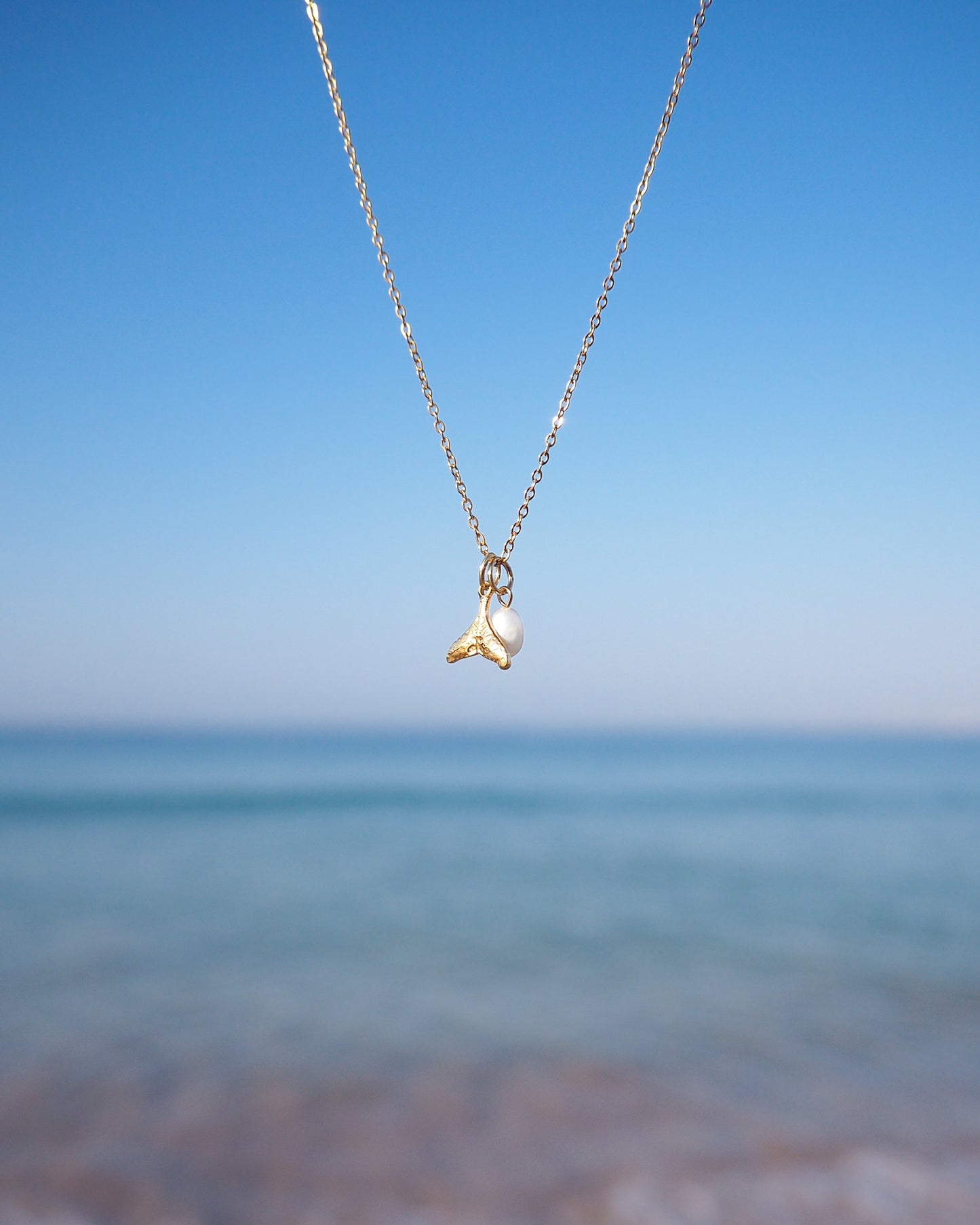 Gold Whale Tail Pearl Necklace with ocean background, 18k gold stainless steel and white freshwater pearl