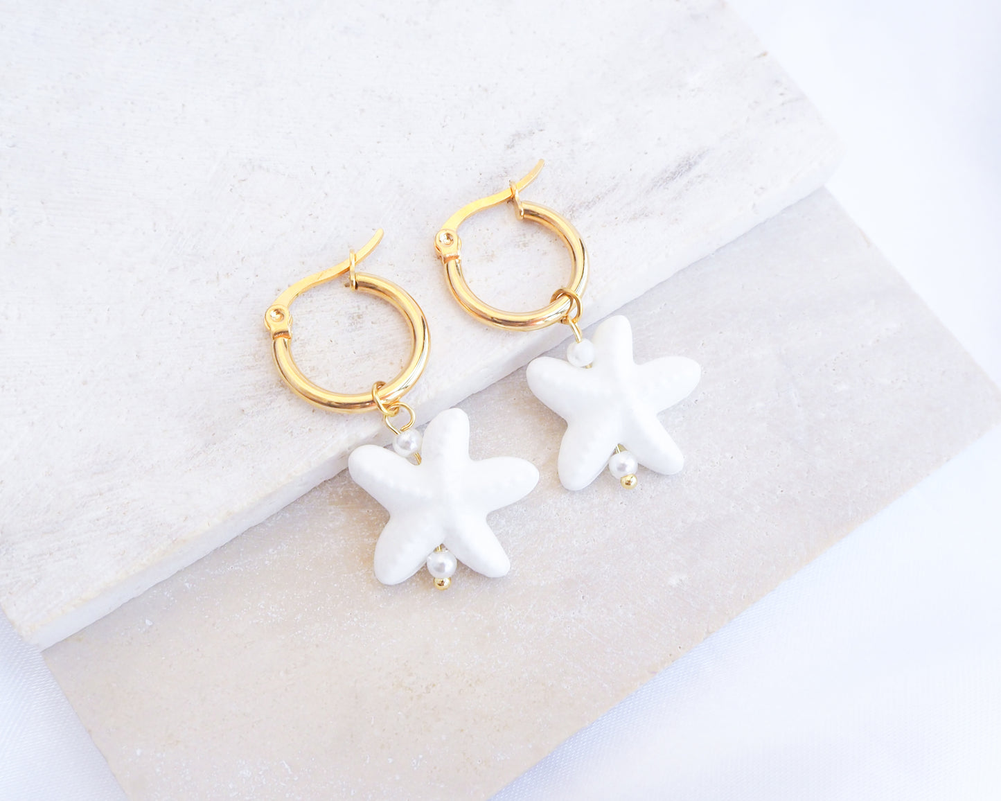 White Ceramic Starfish Gold Earrings on stone, 14k gold stainless steel hoops with white ceramic sea star pendants
