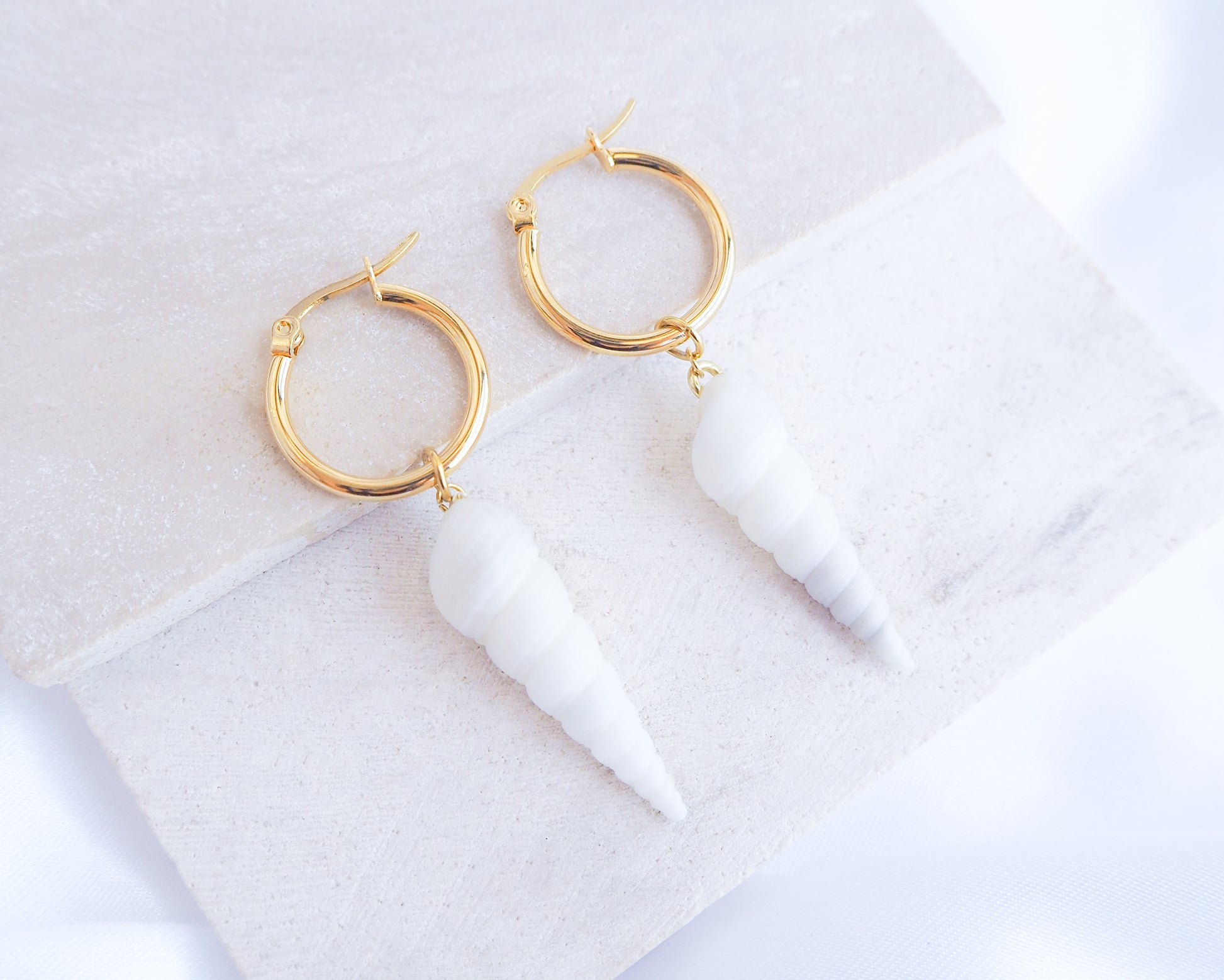 White Common Tower Shell Gold Earring Hoops displayed on stone, handpicked white tower shells from Portugal, 18k gold stainless steel shell earring hoops, seabylou 